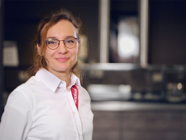 Junge Sodexo Mitarbeiterin mit Sodexo Uniform lächelt 