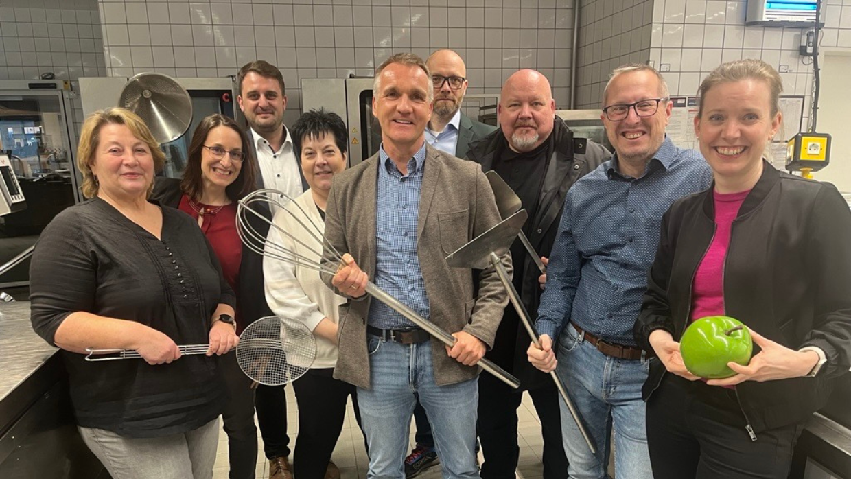 Das Team der Food Platform von Sodexo posiert in einer Großküche für die Kamera.
