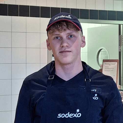 Nachaufnahme von Antonio Ferrary mit Kochschürze und Kappe mit Sodexo-Schriftzug. Antonio macht bei Sodexo eine Ausbildung zum Koch.