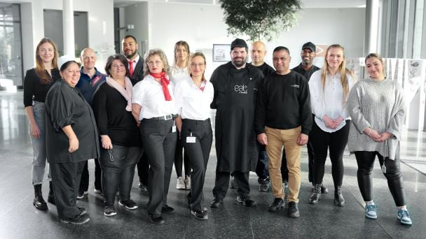 Gruppenbild von 14 Sodexo-Mitarbeitenden mit unterschiedlichen Berufen