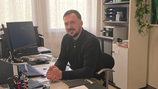 Sodexo Objektleiter Leopold Kolic am Schreibtisch sitzend in seinem Büro.
