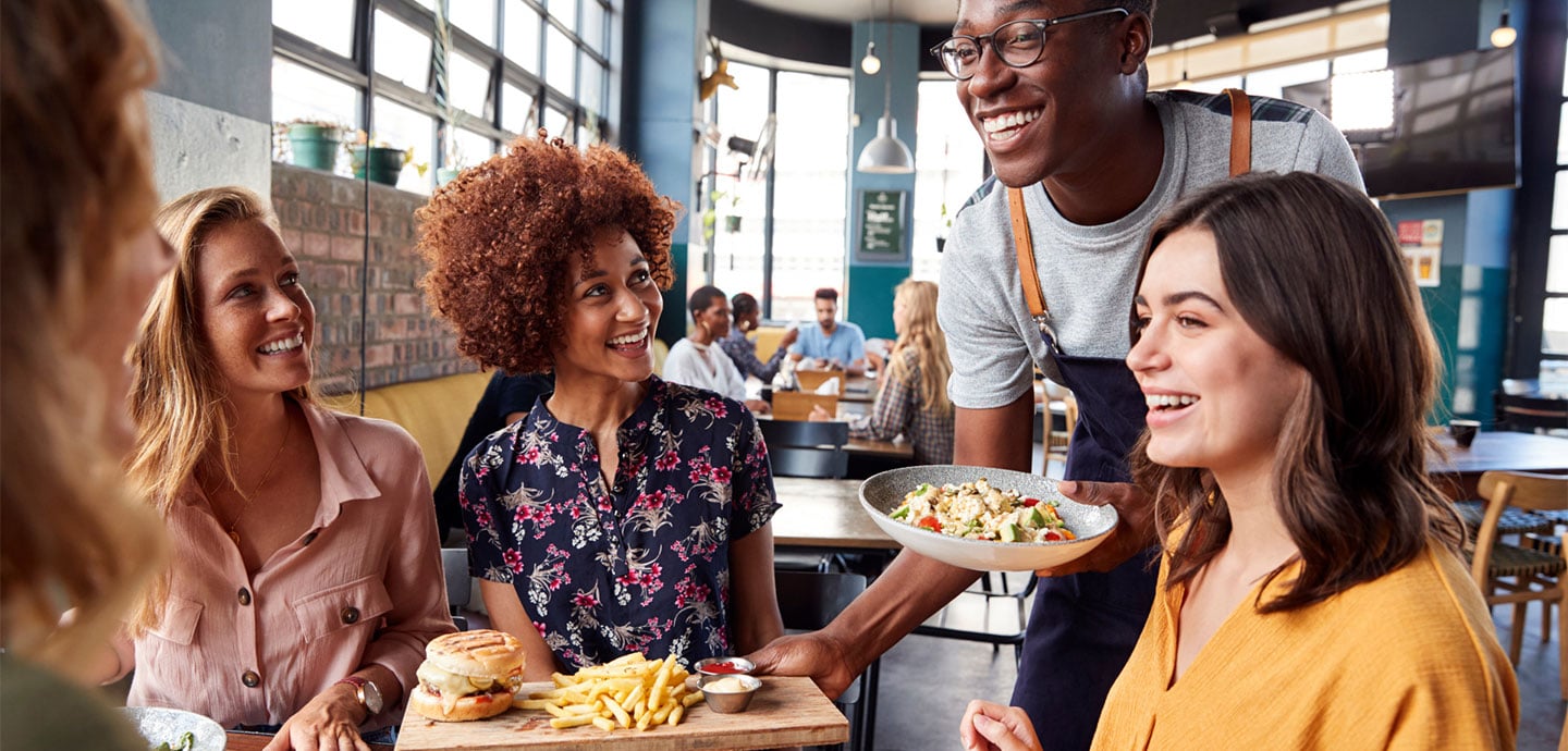 Eine Gruppe von Personen genießt ihr Mittagessen in einem Restaurant und unterhält sich angeregt.