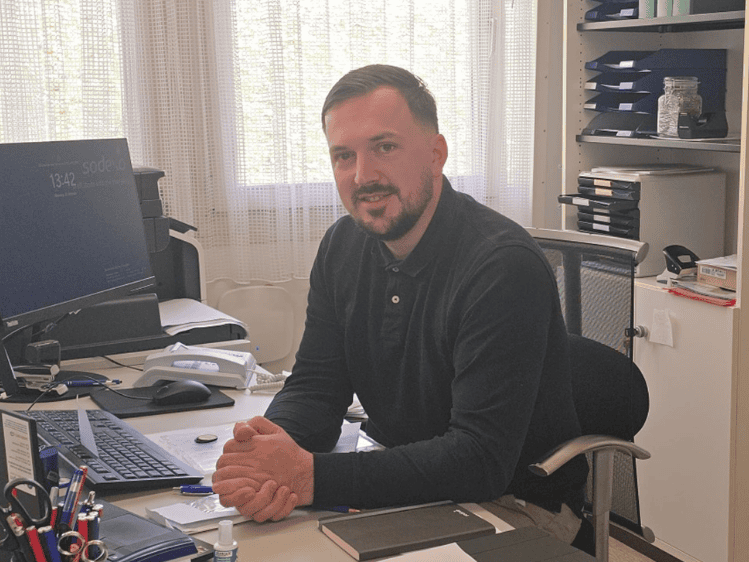 Sodexo Objektleiter Leopold Kolic am Schreibtisch sitzend in seinem Büro.