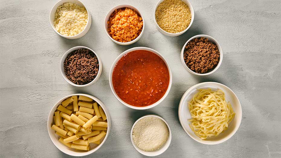 Schüsseln mit den einzelnen Bestandteilen von Spaghetti Bolognese mit den verschiedenen Optionen wie Hackfleisch, pflanzenbasiertes Hack, Parmesan und Butterbrösel