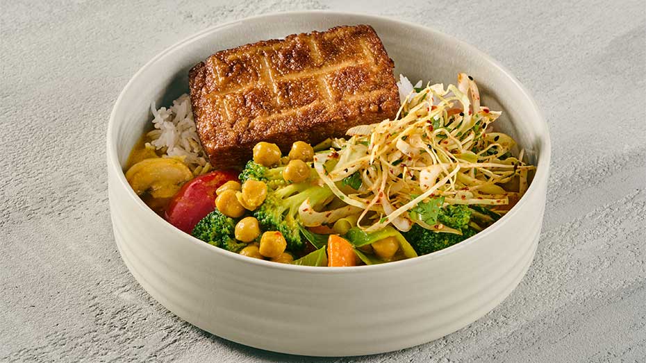 weiße Schale mit Thai Curry von Sodexo mit Reis, Gemüse, Currysauce und gebratenem Tofu.