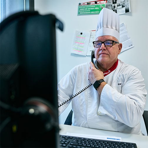 Sodexo-Betriebsleiter Thomas Klatt in seinem Büro am Telefon, während er auf seinen Bildschirm schaut.