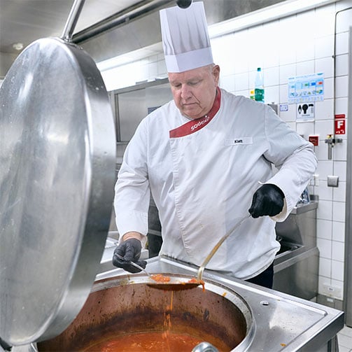 Sodexo-Betriebsleiter Thomas Klatt schmeckt in der Betriebsküche eine Tomatensuppe ab