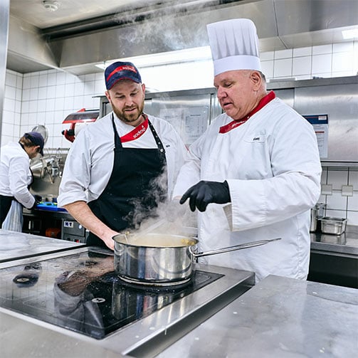 Sodexo-Betriebsleiter Thomas Klatt im Gespräch mit seinem Küchenleiter, während er in einem Topf rührt