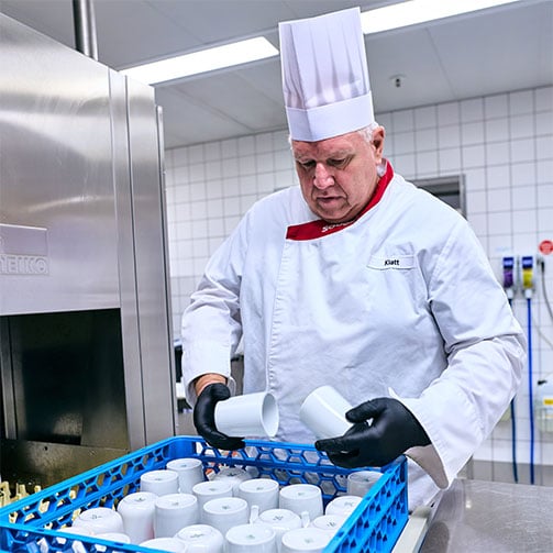 Betriebsleiter Thomas Klatt prüft gereinigte Tassen auf Sauberkeit, nachdem sie aus dem Spülautomaten gekommen sind.