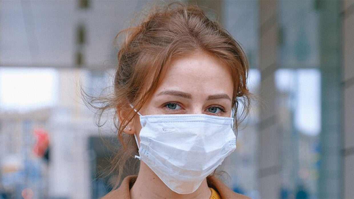 Nahaufnahme Gesicht einer Frau mit Maske vor einem Gebäude