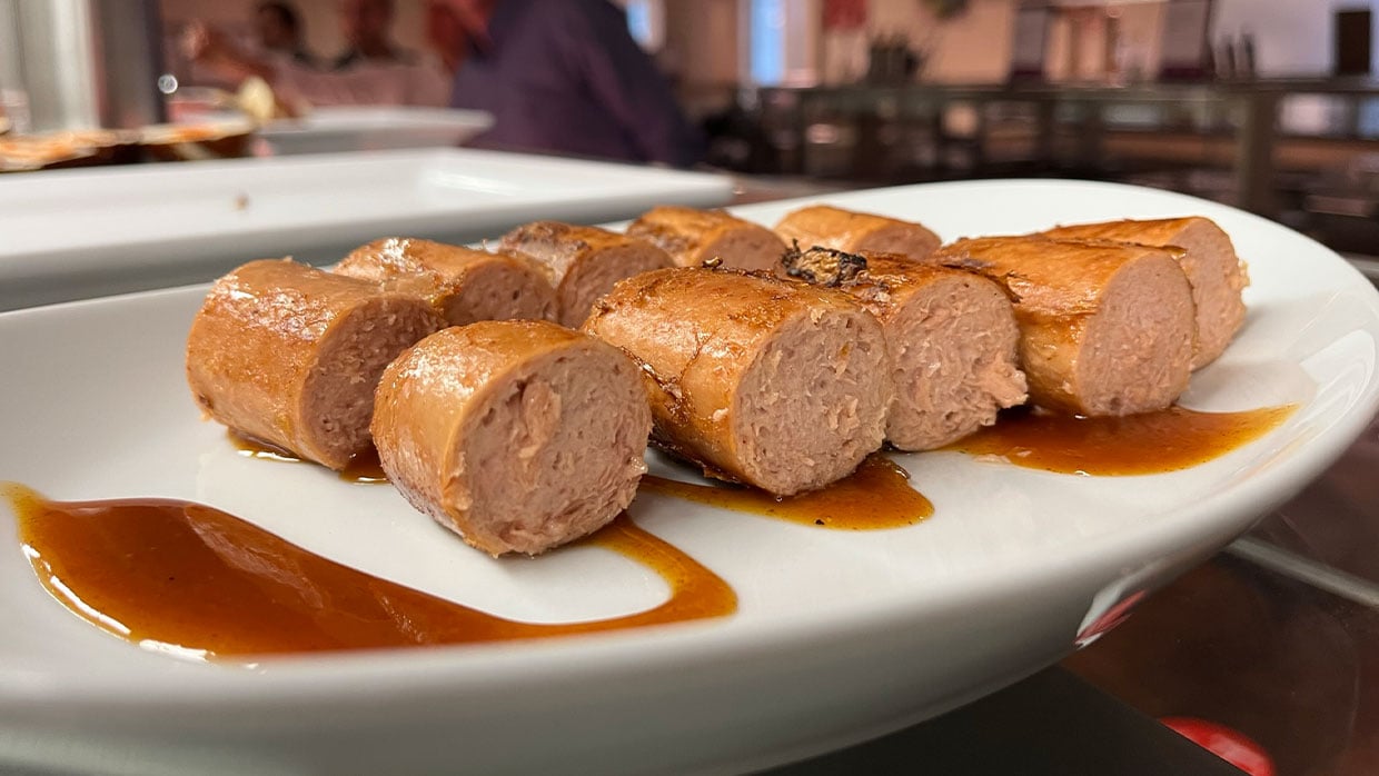 Redefine Meat Bratwurst in Currysauce auf weißem Teller.