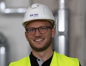 Portrait von Sven Kraus, Projektleiter bei der Sodexo-Tochter GA-tec, auf einer Baustelle mit Helm und Warnweste