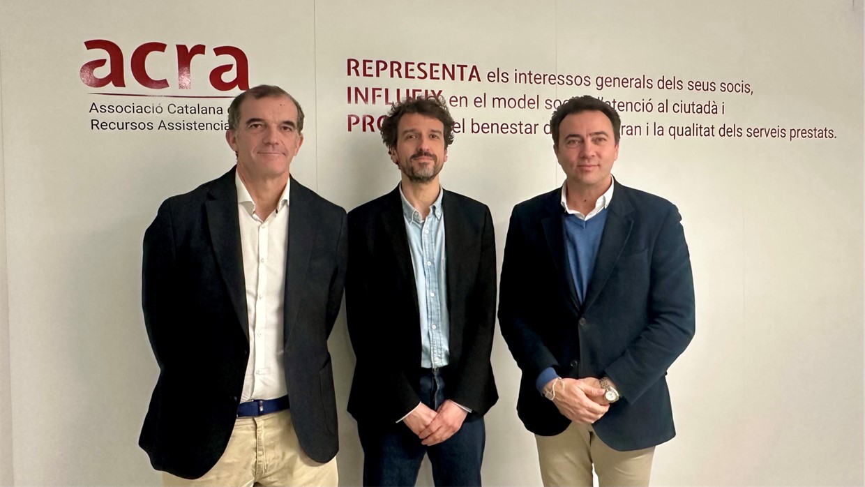 Representantes de Sodexo y ACRA posando ante una pared con la inscripción de ACRA