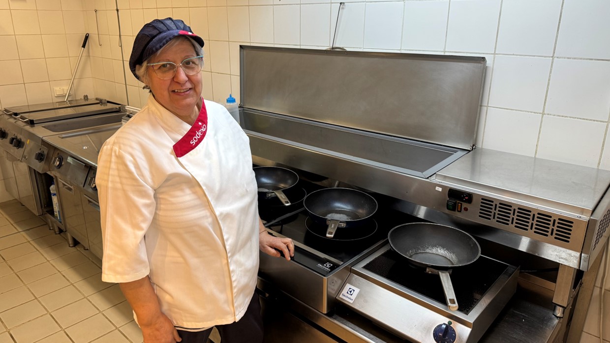 Lola vestida con la chaquetilla de Sodexo delante de una cocina