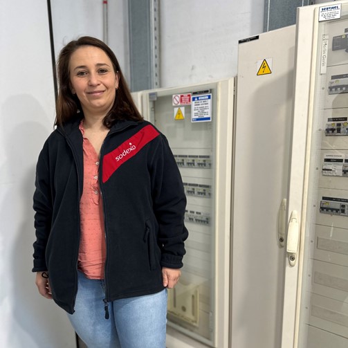 Mujer con chaqueta de Sodexo delante de un cuadro de luces