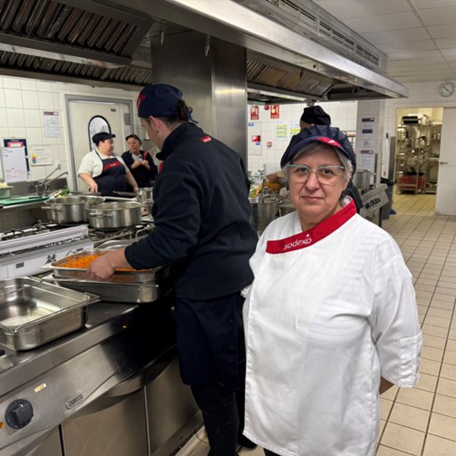 Lola, cocinera, delante de otros cocineros en una cocina de Sodexo