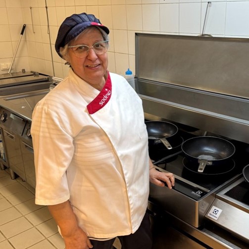 Mujer con chaquetilla de cocinera de Sodexo delante de una cocina