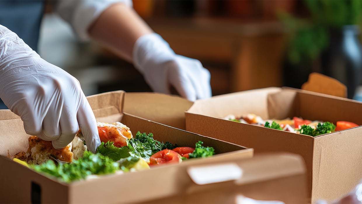 Ruoka-annosten asettelua take away -astioihin.