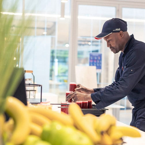 Työntekijä kahvilassa asettelemassa smoothieita esille.