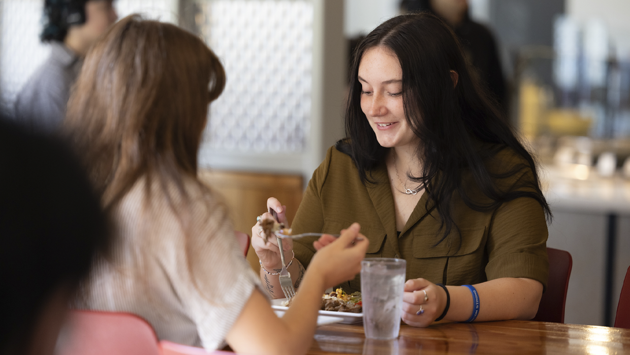 Naisia syömässä ruokapöydän ääressä.