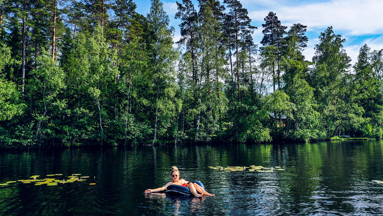 Kuvassa ihminen loikoilemassa uimarenkaan päällä järvellä.