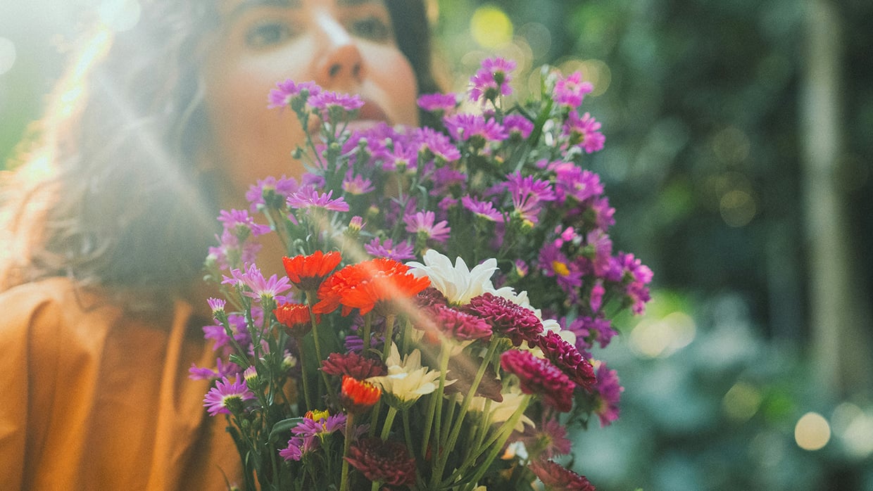 Nainen pitelee käsissään kukkia