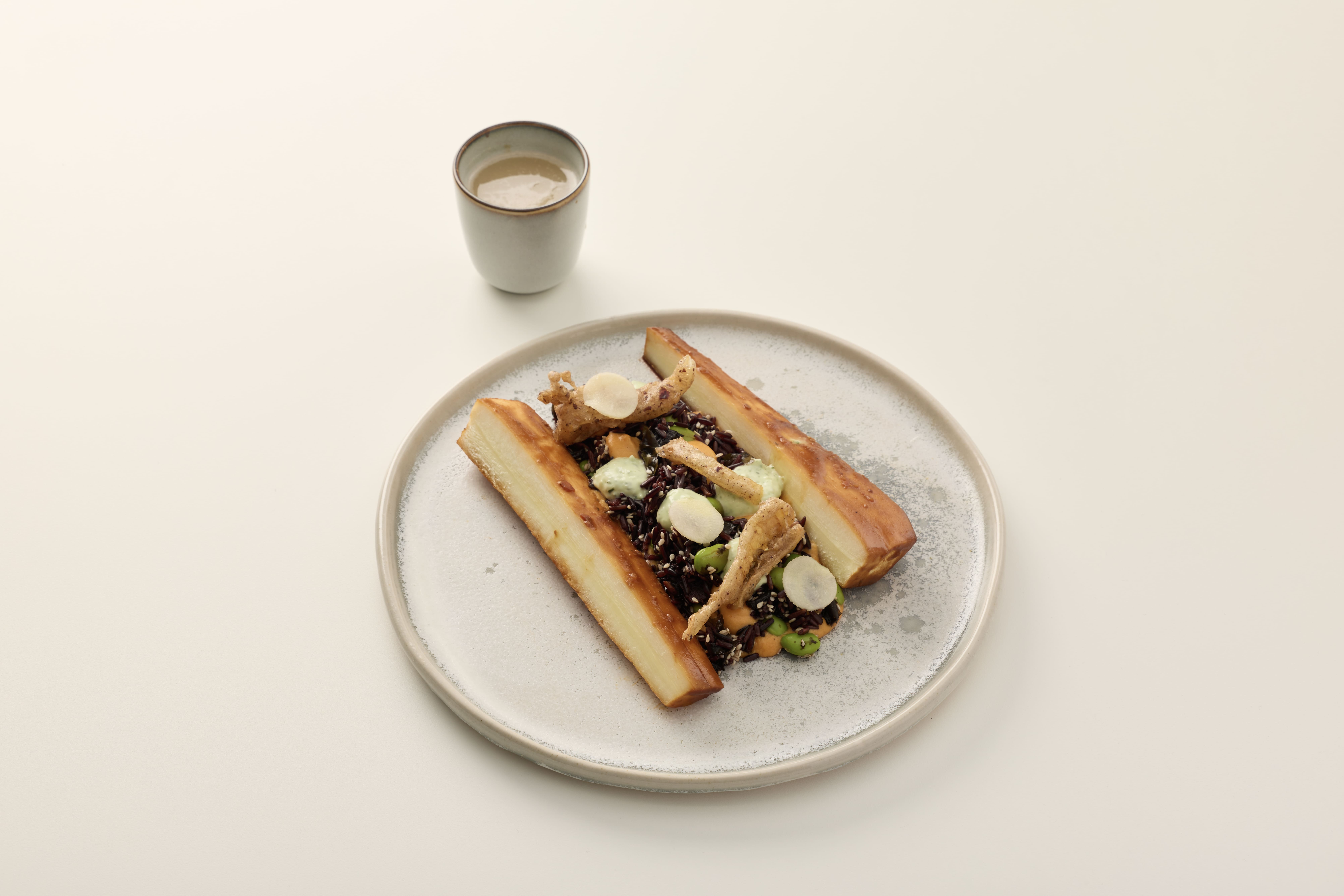 Gordon Carberrys dish - Plated dish with roasted root vegetables, grains, and garnishes, with a small cup of sauce beside it