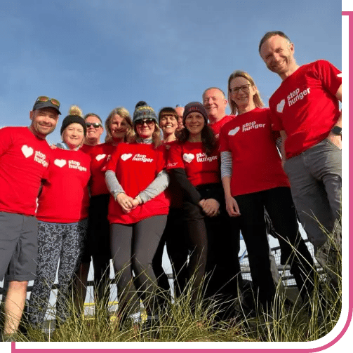 Close-up of volunteers in red ‘stop hunger’ shirts, with overlay text ‘Forging Strong Partnerships To Fight Food Insecurity’ and ‘The Sodexo Stop Hunger Foundation Annual Report 2024