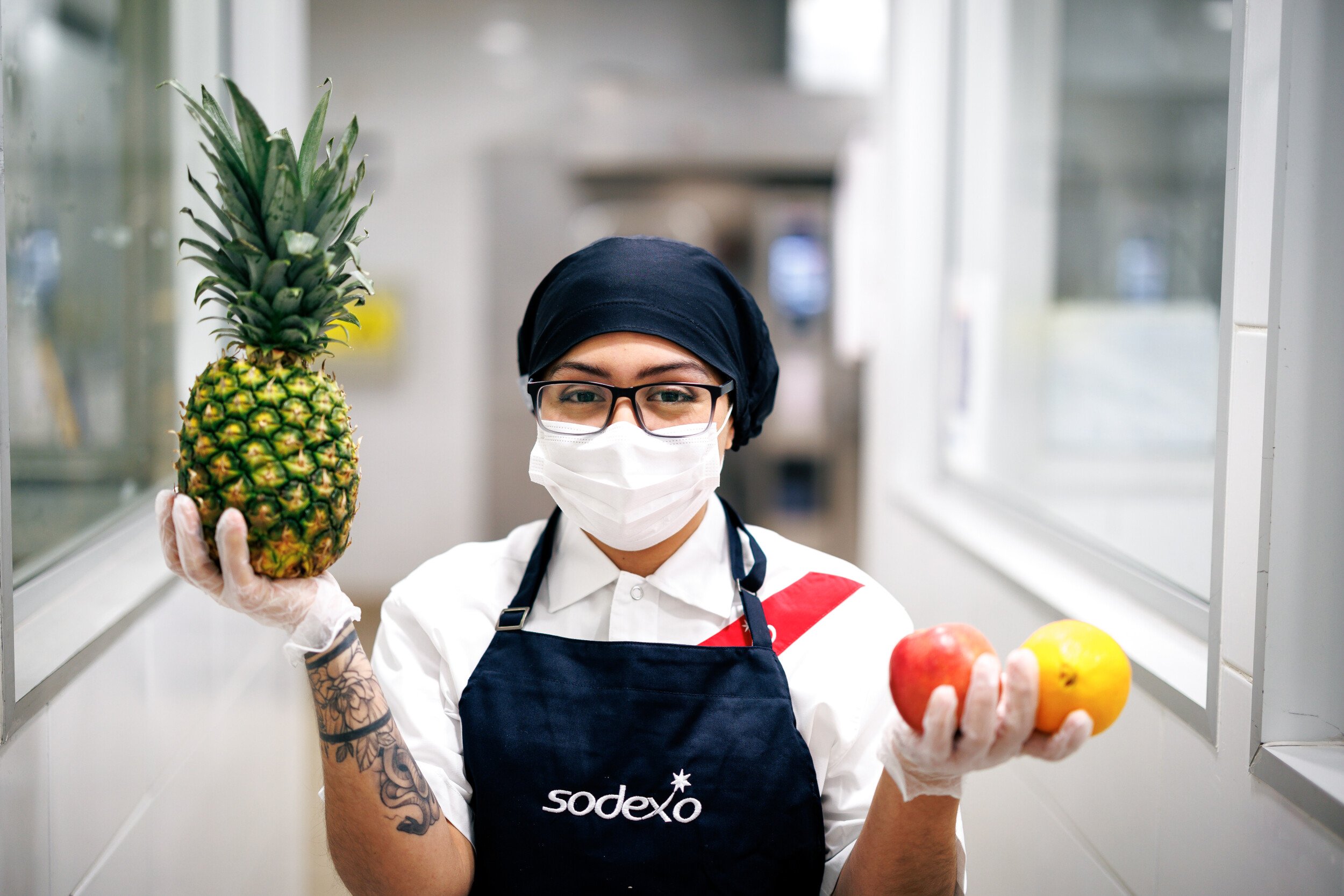 Ragazza con mascherina e grembiule tiene in mano della frutta