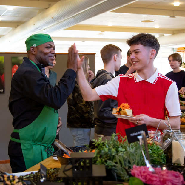 koket medarbetare och elev som gör high five