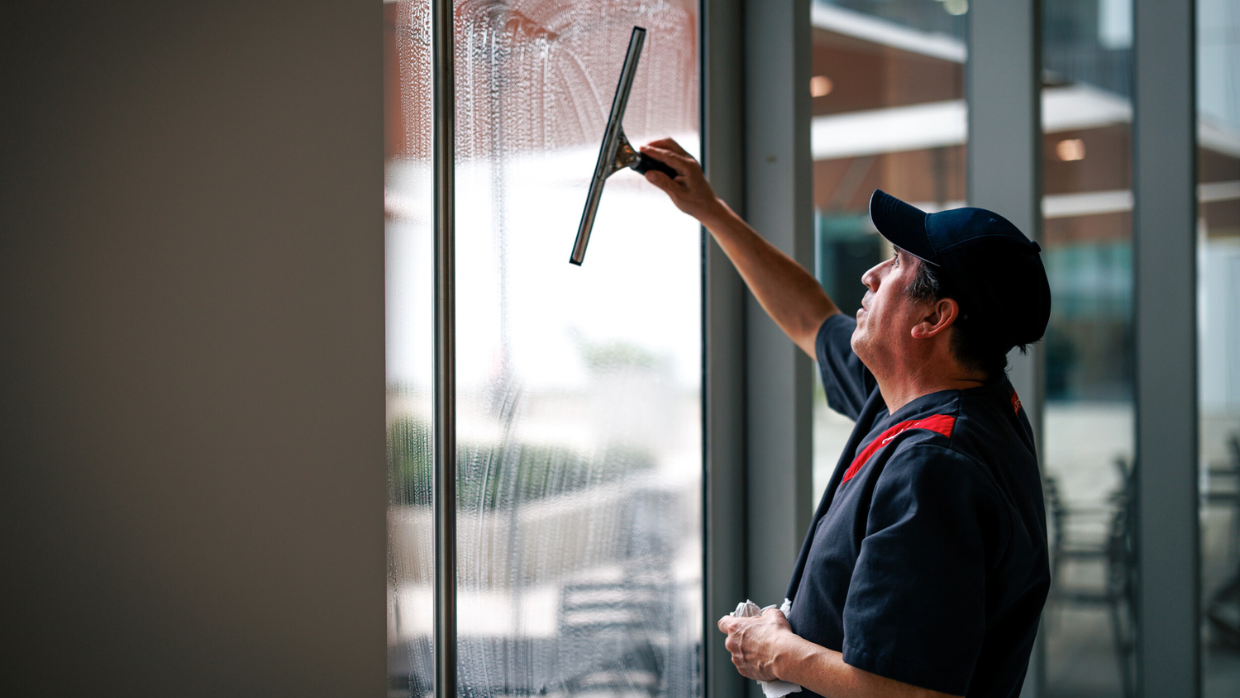 Sodexomedarbetare som tvättar fönster med Svanenmärkta städprodukter