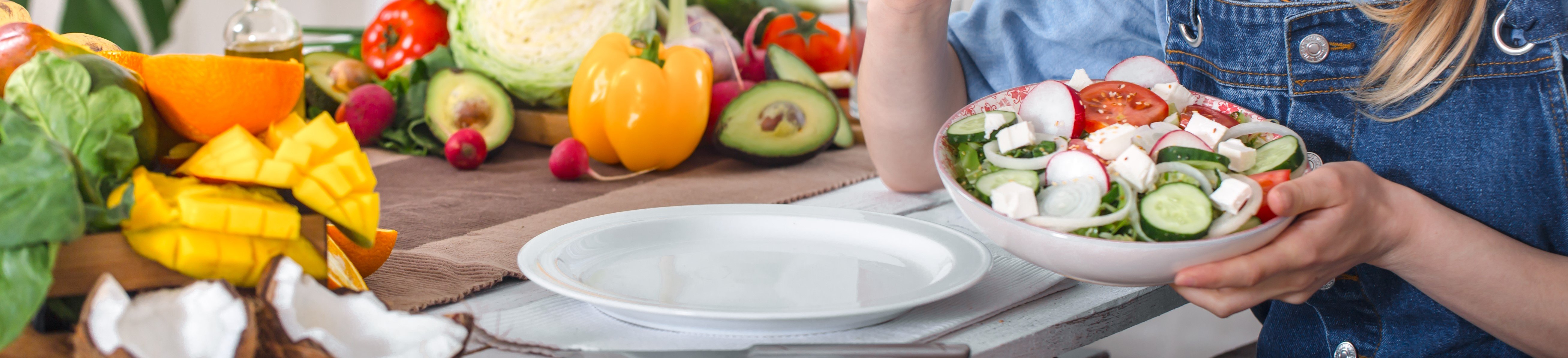 young-happy-woman-eating-salad-with-organic-vegetables-table-light-background-denim-clothes-concept-healthy-home-made-food