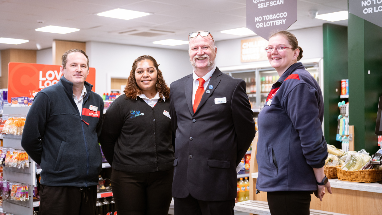 Group of four individuals standing and smiling inside a store.
