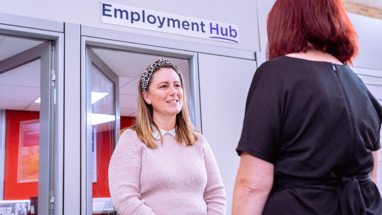 Two women standing in front of an Employment Hub office.