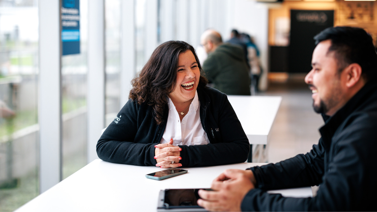 male-and-female-colleagues-laughing-sat-at-table