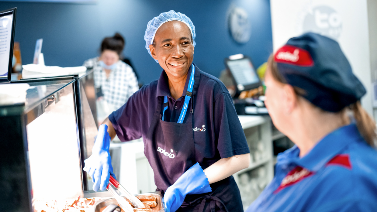 Sodexo kitchen workers in uniforms are serving food.