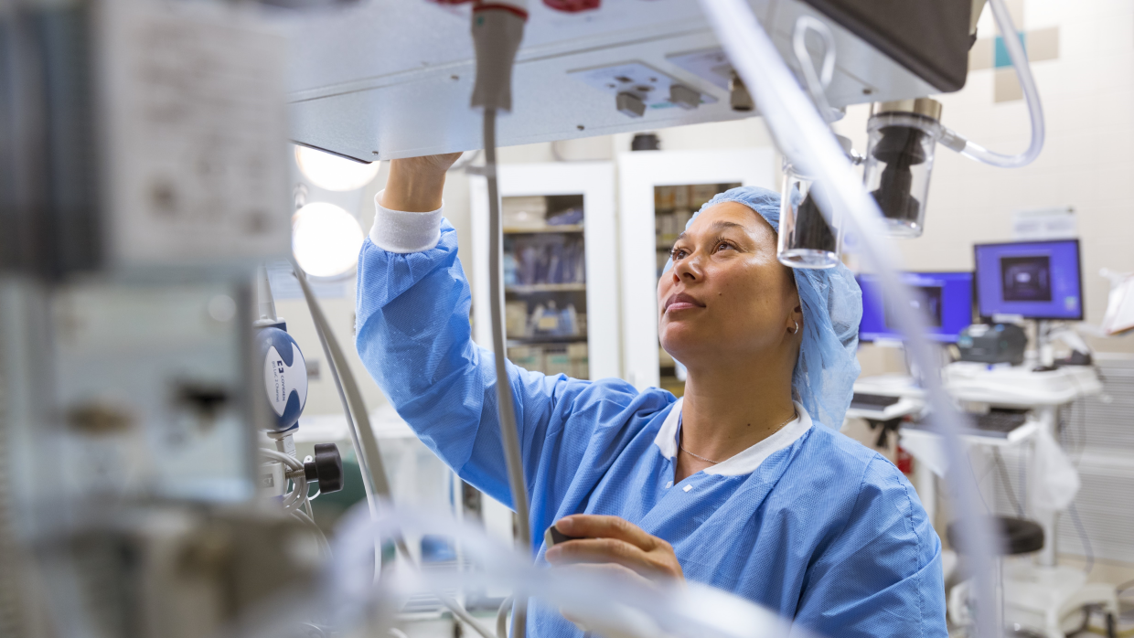 Clinician using medical equipment in a theatre.