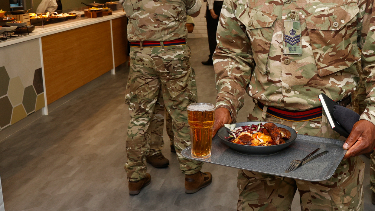 A soldier in uniform holding a tray of food.