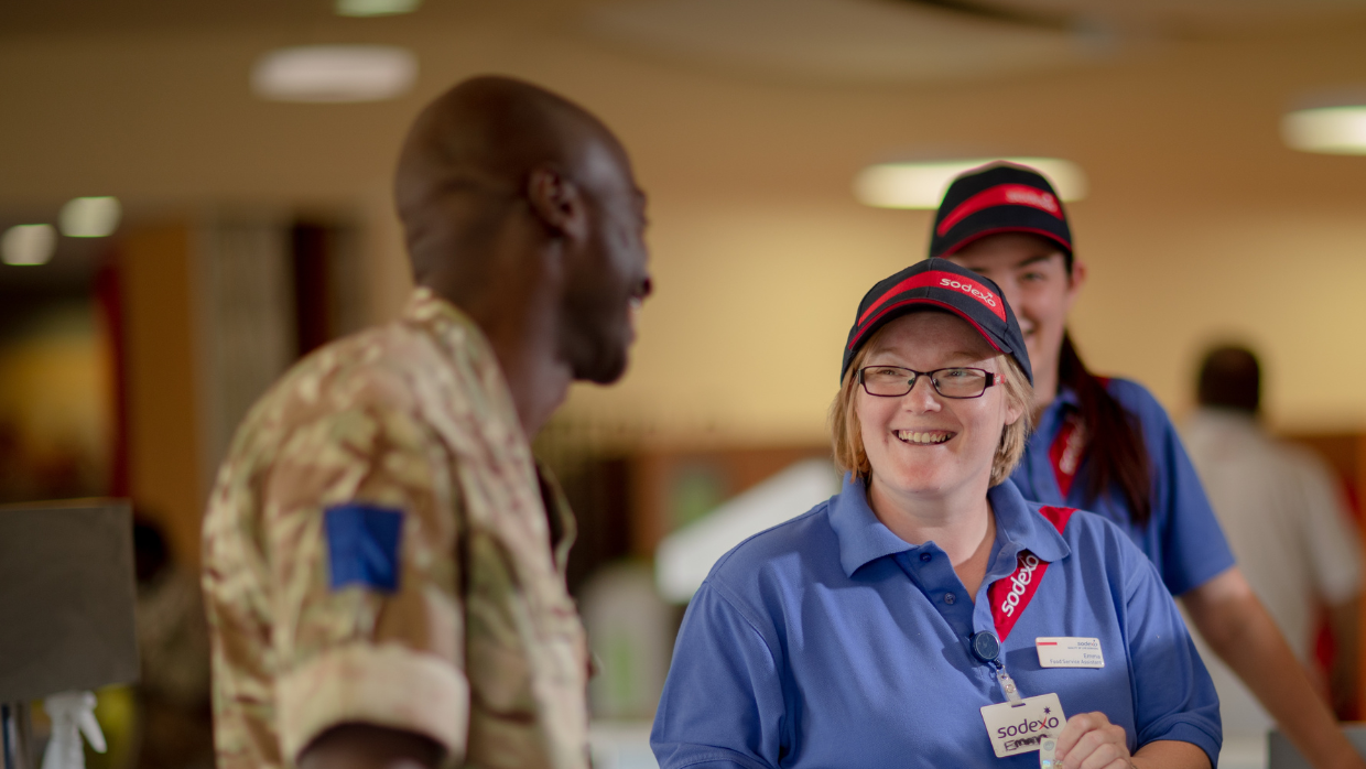 A woman wearing a blue uniform smiling at a soldier.