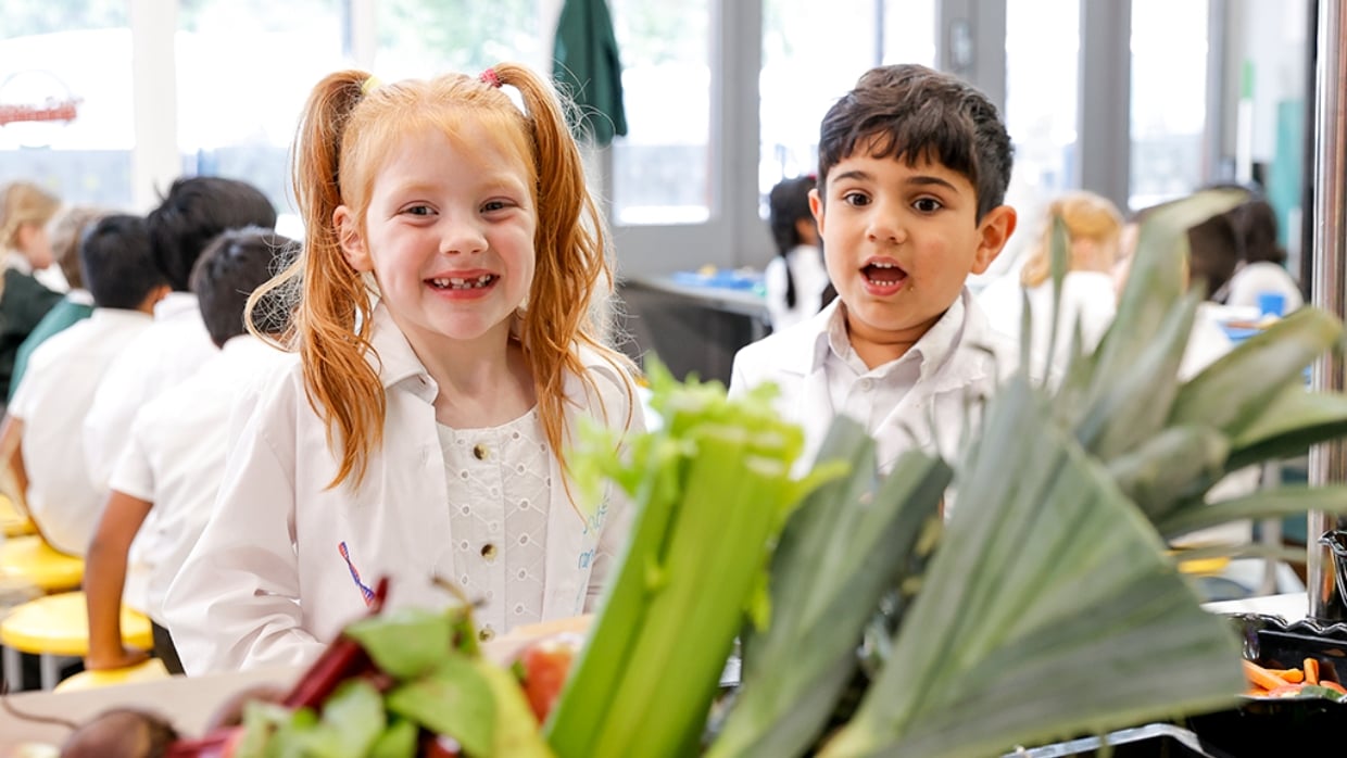happy children at a table with some vegetables