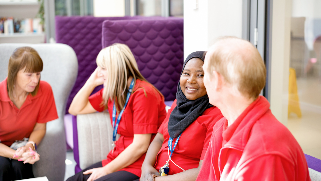 A group of workers in red uniforms sitting and having a discussion.