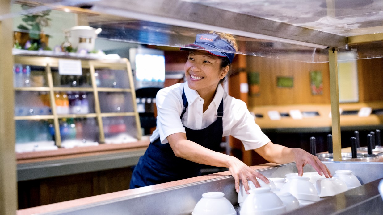 Woman prepaing salad cart smiling at colleague.