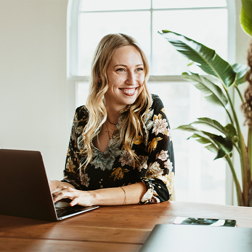 A woman smiling at a laptop