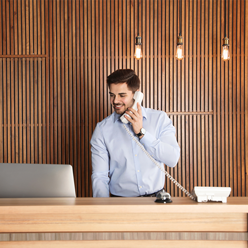 A man taking a phone call at the reception desk in a premium surrounding