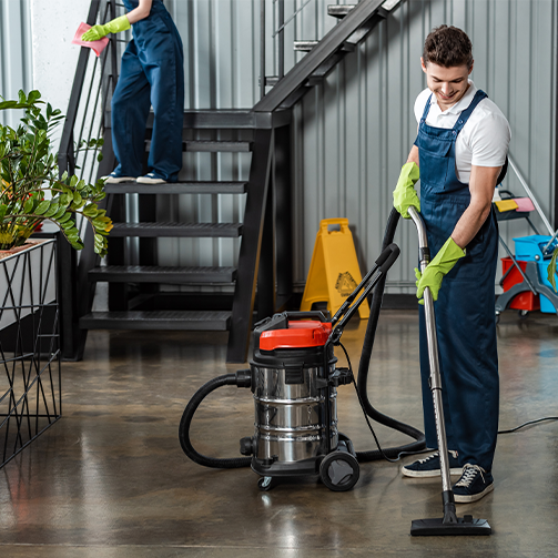 A man in overalls cleaning a room with a vacuum cleaner