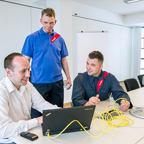 A group of men looking at a laptop discussing