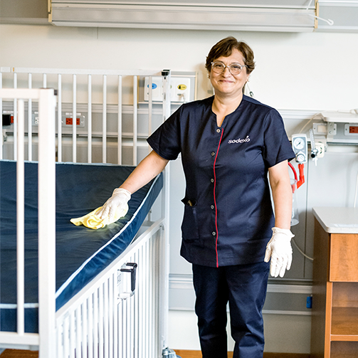 A woman wearing a scrubs and gloves standing in a hospital room