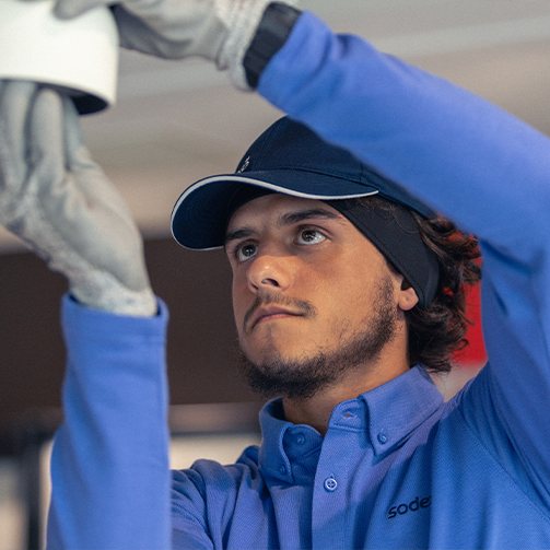 A man wearing a blue shirt and gloves installing a bulb