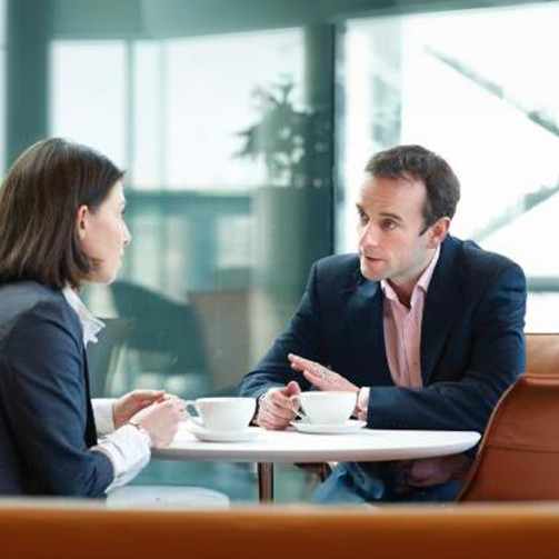 Two individuals engaged in conversation while seated at a table