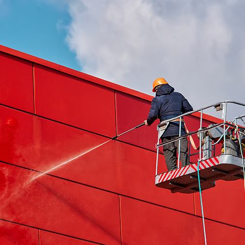 A man on a platform spraying a wall